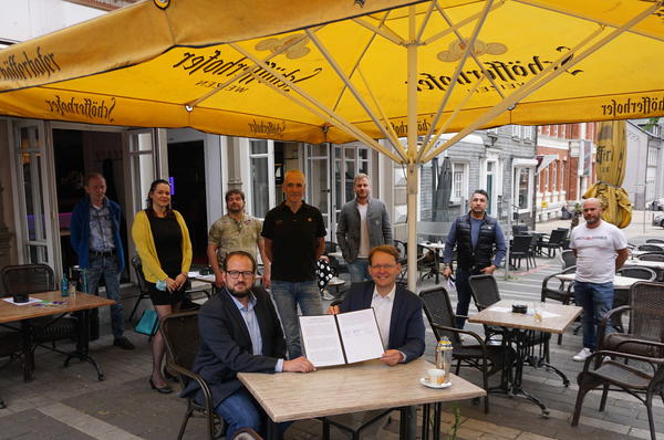 Symbolisch unter einem Schutzschirm unterzeichneten Lars Martin von der DeHoGa, Bürgermeister Claus Jacobi (von links am Tisch) und Wirtevereins-Vorsitzender Ralf Hedtmann (dahinter) die Gevelsberger Erklärung.