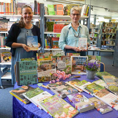 Stefanie Kron (links) und Gabriele Linden präsentieren eine Auswahl an Gartenbüchern, die in der Stadtbücherei zu finden sind.