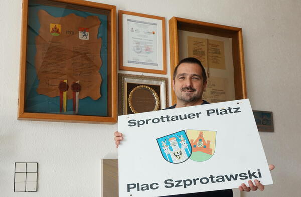 Marco Marcegaglia mit dem abmontierten Schild vom Sprottauer Platz. Dahinter die Partnerschafts-Urkunden im Foyer vor dem Ratssaal.