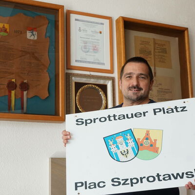 Marco Marcegaglia mit dem abmontierten Schild vom Sprottauer Platz. Dahinter die Partnerschafts-Urkunden im Foyer vor dem Ratssaal.