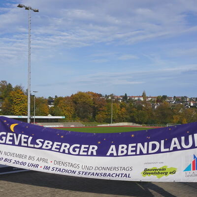 Sie freuen sich auf den Abendlauf: Sportsachbearbeiterin Anette Figge-Kinner und Nikolai Markiw vom Stadionteam mit dem Banner für die Veranstaltungen im Stefansbachtal.